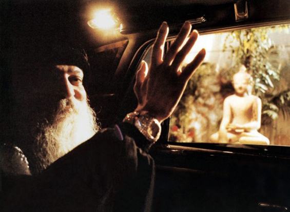 Osho waving past Buddha statue