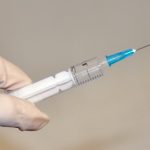 Hand holding syringe Feat.