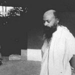 Osho standing in courtyard Feat
