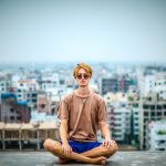 Young man meditating on roof