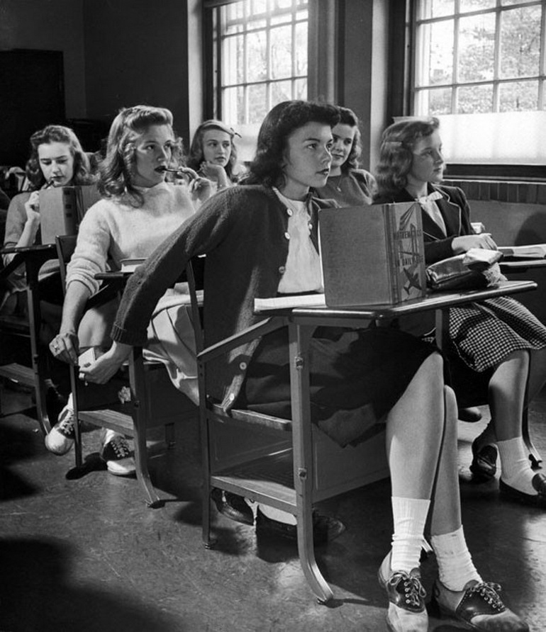 girl passing message on paper to pupil behind