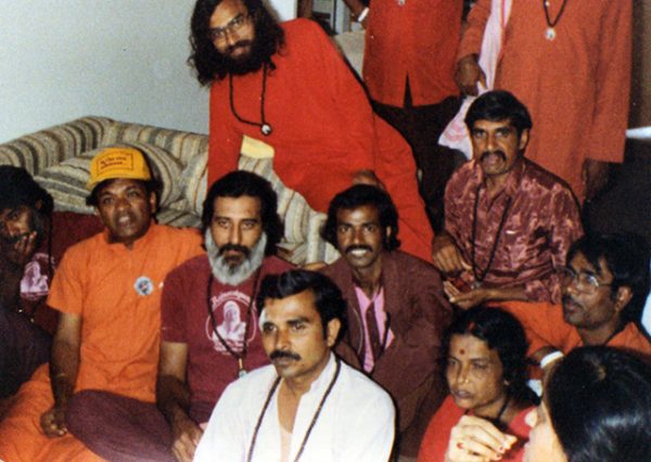 Leaning on couch behind Vinod Bharti
