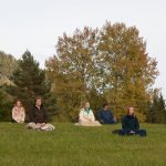 People meditating in field